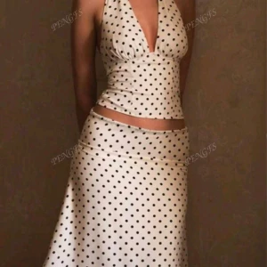 Vit prickig långkjol - Supersnygg vit långkjol med svarta prickar. Kjolen har en mjuk, svepande form och sitter snyggt på höften. Perfekt för dig som gillar en trendig och feminin look.