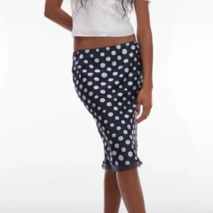 Svart prickig långkjol med spetskant - Snygg svart långkjol med vita prickar och smal passform. 