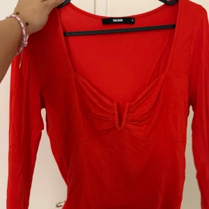 Röd långärmad topp från Bik Bok - Snygg röd långärmad topp från Bik Bok med djup v-ringning och rynkade detaljer vid bysten. 