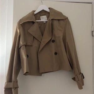 Trenchcoat  - Säljer denna super snygga trenchcoaten från H&M, använd ett par gånger. Har lite sminkfläckar vid kragen