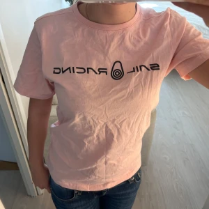 Rosa Sail Racing t-shirt - Säljer en peachrosa t-shirt från Sail Racing, knappt använd och i storlek 160