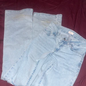 Ljusblå bootcut jeans från Nelly - Ljusblå jeans från Nelly med bootcut-ben och slitningar på knäna. Jeansen har klassisk femficksdesign och bakfickor med rosa broderad detalj. Tillverkade i jeansmaterial med en snygg, avslappnad vibe.  Ny pris är 699kr. Jeansen är andvända ett få anfall gånger. Skriv för fler bilder/frågor