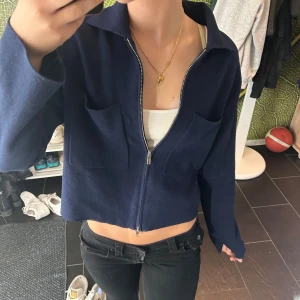 Mörkblå kofta från Åhléns  - Säljer en mörkblå kofta med dragkedja framtill och två stora bröstfickor. Jackan har lång ärm, klassisk krage och är tillverkad i ett stickat material som känns mjukt och skönt. Perfekt för dig som gillar en clean och stilren look. Ord pris 600kr