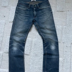 Acne Studios blå jeans straight fit - Säljer ett par klassiska blå jeans från Acne Studios med snyggt slitna detaljer och raka ben. Jeansen har fem fickor, normal midja och är tillverkade i robust denim. Perfekta för dig som gillar en tidlös och avslappnad stil.