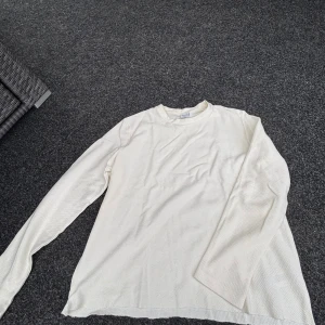 Vit långärmad tröja från Bershka - Vit långärmad tröja från Bershka i storlek M. Tröjan har en enkel och clean design med rund hals och är tillverkad i ett mjukt, strukturerat bomullsmaterial. Perfekt för dig som gillar minimalistisk stil och vill ha något bekvämt och snyggt.