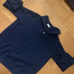 Mörkblå stickad tröja med dragkedja - Säljer en snygg mörkblå stickad tröja med quarterzip upptill. Perfekt för kyliga dagar och passar både till vardags och lite finare tillfällen. Tröjan har långa ärmar och en bekväm passform. bra skick inte använd mycket alls.