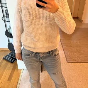 Beige stickad tröja med lång ärm - Säljer en beige stickad tröja med lång ärm och rund hals. Tröjan har en grovstickad struktur och ribbade muddar vid ärmslut och nederkant. Perfekt för lager-på-lager och enkel att matcha med jeans eller kjol.