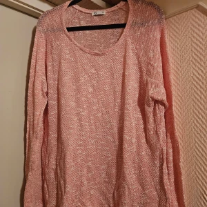 Ljusrosa stickad tröja från C, XL - Luftig och stickad tröja i ljusrosa nyans från C i storlek XL. Tröjan har rund halsringning och långa ärmar, perfekt för lager-på-lager. Den stickade strukturen ger en avslappnad och trendig vibe.