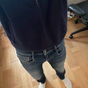 Replay Anbass jeans blå, stl 29 - Säljer ett par Replay Anbass jeans i blå tvätt med snygga slitningar. Jeansen har smal passform och är tillverkade i stretchigt denim för extra komfort. Perfekta för dig som gillar en modern och stilren look.