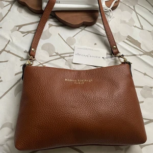 New Maison Héritage Sally handbag - New Maison Héritage Sally handbag, color: camel • Product number: ZZO2E8W31-B01 	•	Shoulder strap: Detachable 	•	Spacious interior with a zip pocket 	•	Usage: Can also be carried as a clutch for special occasions 	•	Closure: Zipper 	•	Material features: Long-lasting durability 	•	Outer material: Leather 	•	Lining: Textile  Dimensions: 	•	Length: 26 cm 	•	Width: 5 cm 	•	Height: 18 cm 	•	Handle drop: 31 cm. More pictures: https://www.vinted.fi/items/7142243071-maison-heritage-sally-handbag