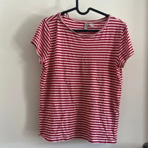 Randig t-shirt  - Röd- och vitrandig t-shirt från H&M Divided med klassisk rund hals och korta ärmar. 