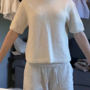 Vit stickad tröja från Gina Tricot - Supermjuk och stilren vit stickad tröja från Gina Tricot. Tröjan har korta ärmar, rund halsringning och ribbade kanter. Perfekt för lager-på-lager och funkar året runt för en clean look.