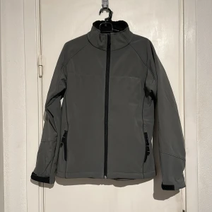 Helt ny jacka   - Helt ny jacka med hög krage och hel dragkedja framtill. Jackan har två sidofickor med dragkedja och flera innerfickor. Justerbara ärmslut med kardborre. 