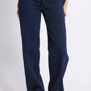 Mörkblå mjukisbyxor med snörning - Mörkblå mjukisbyxor med raka ben och bred resår i midjan. Byxorna har snörning framtill och är tillverkade i mjukt material som känns skönt mot huden. Perfekta för chill dagar eller när du vill vara bekväm men ändå se snygg ut. Det är helt oanvända, jag köpte de och glömde lämna tillbaka, skulle lämna tillbaka för att de var förkorta men det blev försent för att lämna tillbaka 