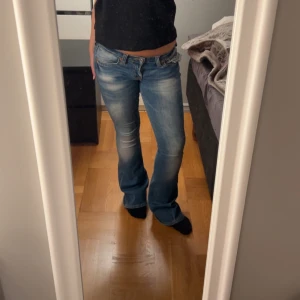 Blå bootcut jeans från True Religion - Säljer ett par blå bootcut jeans från True Religion med låg midja och klassiska kontrastsömmar. Jeansen har broderad ficka bak och tydliga slitningar för en cool look. Helt nytt skick. Pris kan diskuteras.