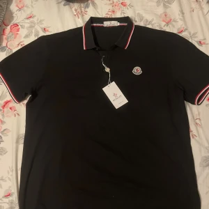 Svart pikétröja från Moncler - Helt ny oanvänd, står 3XL men passar som L-XL, måtten finns där så mätt gärna med något av plaggen du har hemma för att jämföra ‼️