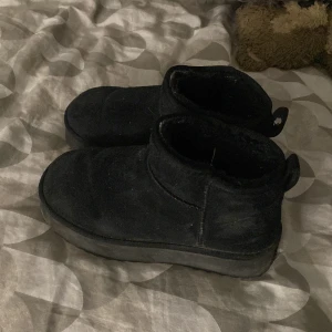 Svarta mockaboots med platt sula - Säljer ett par svarta boots i mocka med platt sula och rund tå. Skorna är fodrade och har en enkel, stilren design med låg skaft och dragflik bak. Perfekta för kyligare dagar och passar till många olika outfits. Använts 3 gånger och är i storlek 37
