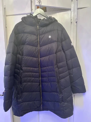 Svart pufferjacka från Áhkká Renata - Säljer en svart pufferjacka från Áhkká by Renata med huva och snygga logodetaljer på bröstet och ärmen. Jackan har dragkedja framtill och två sidofickor med dragkedja. Perfekt för kalla dagar med sin quiltade design och oversized passform. Hör av er vid intresse💞