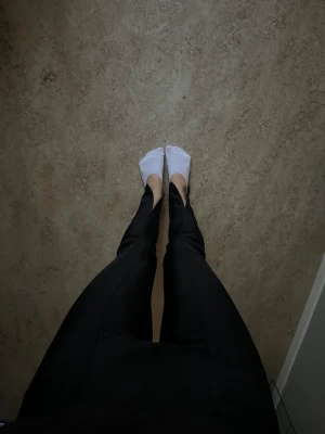 Svarta byxor med slits - Säljer ett par svarta byxor med slits framtill vid benslut. Byxorna har hög midja och sitter tight över benen med en rakare passform nedtill. Mycket fint skick!! 