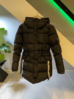 Everest W Warm Parka - Jackan är vadderad med en dunliknande syntetfyllning av 100% återvunnen polyester. Den har ett yttertyg som är vind- och vattentätt. Den längre parkamodellen har en praktisk dragkedja i sidorna som gör det enkelt att öppna upp nedtill, till exempel när du ska sätta dig ner eller kliva in i bilen. Ny pris 1499kr! Länk till stadium: https://www.stadium.se/sport/alla-klader/jackor/405139101/everest.w-warm-parka.black.    