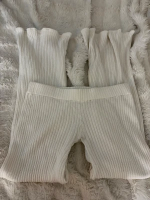 Lågmidjade mjukisbyxor  - Säljer dessa sköna stickade byxorna som är sydda lågmidjade. Ribbad design och väldigt mjukt material, inte stickigt. Beige/cremevit färg. Väldigt stretchiga. Midjemått rakt över: 38cm och innerbensllängd: ca 74cm