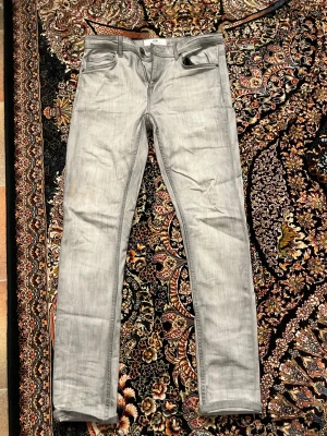 Grå jeans från FSBN, storlek 30/32 - Snygga grå jeans från FSBN Original Denim Company i storlek 30/32. Modellen har klassisk femficksdesign, raka ben och diskreta sömmar. Jeansen är tillverkade i ett mjukt bomullsmaterial med en lätt tvättad look och passform som sitter skönt. Köpte dom från new Yorker och kostade 230kr.