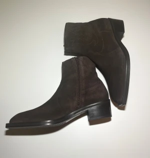 Chelseaboots med klack och sömmar i cowboystil  - Helt oanvända mocka-boots från asos. Varan är slutsåld på hemsidan och nu säljs de för billigare pris. Kontakta gärna vid frågor eller funderingar.