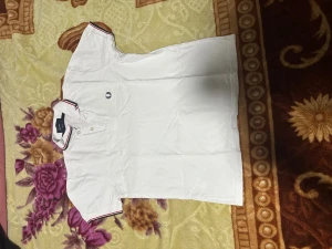 Vit Fred Perry piké med röd och svart kant - Vit pikétröja från Fred Perry i slim fit-modell. Klassisk krage med röda och svarta ränder på krage och ärmslut. Broderad Fred Perry-logga på bröstet och knappar framtill. Perfekt för en clean och sportig stil.