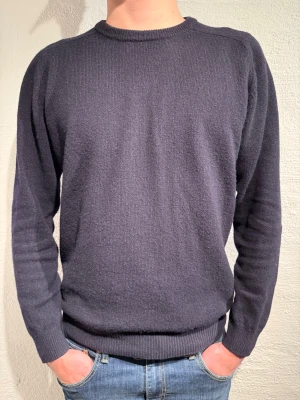 Mörkblå stickad tröja Alan Paine - Snygg mörkblå stickad tröja från Alan Paine i ren lammull. Riktigt skönt material som är perfekt för lite kallare tider. Tröjan är knappast använd, endast ett fåtal gånger. Storlek EU 50 vilket motsvarar M. Skriv vid minsta fundering.