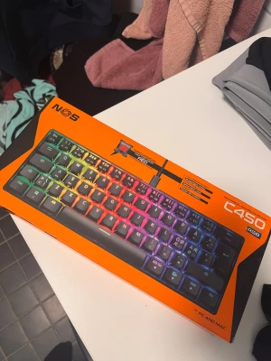 NOS C450 RGB Mechanical Mini Pro Keyboard - NOS C450 RGB är ett kompakt mekaniskt tangentbord med linjära röda switchar och RGB-belysning. Passar både PC och Mac. Levereras i originalförpackning, ser oanvänt ut och är perfekt för gaming eller arbete där platsbesparing och snabb respons är viktigt.