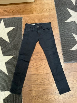 Replay Anbass svarta slim jeans, stl 33 - Svarta Replay Anbass Hyperflex jeans i slim fit med klassisk femficksdesign. Jeansen är tillverkade i stretchigt material för extra komfort och har en snygg, smal passform. Perfekta för dig som gillar stilrena och moderna jeans med lite edge.