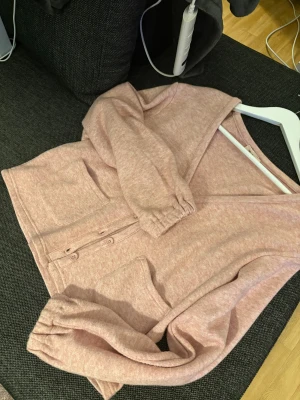 Rosa kofta från Nelly med fickor - Mysig rosa kofta från Nelly med v-ringning och knappar framtill. Koftan har två stora fickor och långa ärmar med resår vid handlederna. Materialet är mjukt och känns som bomull, perfekt för chill dagar. Passformen är loose och färgen är ljusrosa.