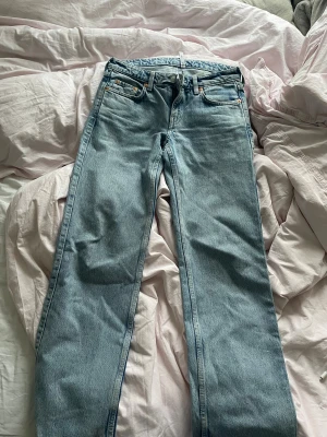 Weekday Arrow ljusblå  jeans - Arrow jeans i ljusblå tvätt med klassisk femficksdesign och raka ben. Jeansen har normal passform och är tillverkade i bomull. Snygga detaljer med kopparfärgade nitar och knappstängning framtill. Perfekt för dig som gillar en clean och enkel jeanslook. W36, L30
