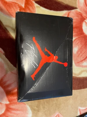 Svarta Nike Jordan 4 sneakers - Nike Air Jordan 4 sneakers i helsvart färg med snygga meshpaneler och detaljer i syntet och skinn. Klassisk Jumpman-logga på tungan och sulan, samt snörning och platt sula. Kommer med originalbox och tag. Perfekt för dig som gillar streetwear och basketstil.