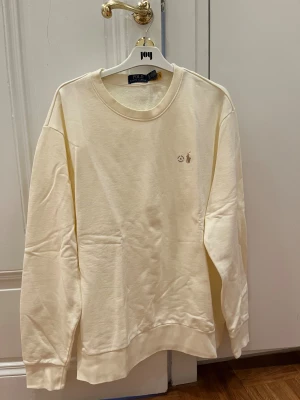Krämvit sweatshirt från Polo Ralph Lauren - Snygg krämvit sweatshirt från Polo Ralph Lauren. Storlek XL, aldrig använd och taggen finns kvar