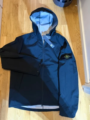 Svart vind & regn - jacka Stone Island - Storlek M, oanvänd. Lite stor i storleken (längdenk) Passar perfekt om man vill ha den lite under midjan. 