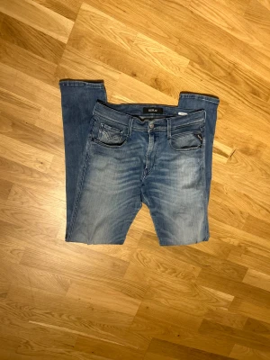 Replay blå jeans med slitning - Snygga blå jeans från Replay i slitning på ena benet. Jeansen har en ljus tvätt med snygga replay detaljer w31 L34