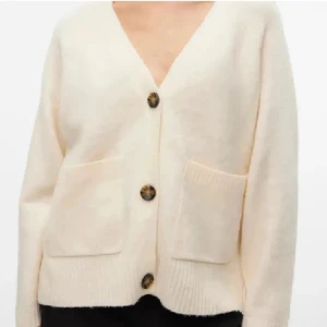 Beige kofta från Vero Moda - Mysig beige kofta från Vero Moda med v-ringad hals och stora bruna knappar framtill. Koftan har två rejäla fickor och ribbade muddar vid ärmslut och nederkant. Perfekt för lager-på-lager och chill stil.  Använd ca 2 gånger så i ny skick💕