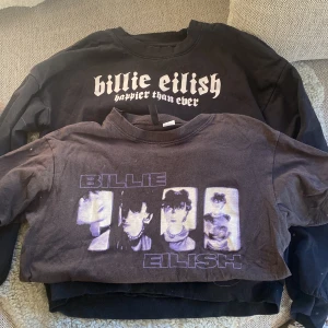 Billie Eilish tröjpaket XS & 170 - Två snygga tröjor med Billie Eilish-tryck. Den ena är svart sweatshirt med 'happier than ever' och stor vit bild på Billie, storlek 170 från Cubus. Den andra är en mörk t-shirt från H&M Divided i XS med lila och vit grafik av Billie Eilish. Perfekt för fans som vill sticka ut.
