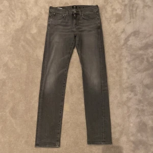 Grå Edwin ED-80 slim tapered jeans - Snygga grå jeans från Edwin, modell ED-80 slim tapered. De har klassisk femficksdesign, smal passform och avsmalnande ben. Jeansen är tillverkade i mjukt denimtyg och har subtila slitningar för en cool look. Perfekt för dig som gillar stilrena och moderna jeans. OBS: DESSA JEANS ÄR KRYMPTA OCH SITTER I MINDRE SIZE
