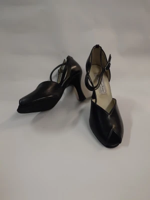 Svarta Dansskor med öppen tå och klack - Snygga svarta  från Werner kern med elegant klack och öppen tå. Skorna har en rundad form och ett smidigt spänne runt ankeln. Tillverkade i skinn för en lyxig känsla och passar perfekt till dig som gillar stilrena och klassiska skor. Nypris 1500-1800kr