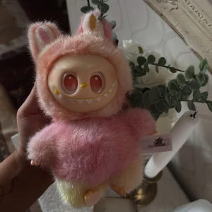 Labobu  - Söt samlarfigur från Pop Mart Big into Energy-serien, modell 'Serenity'. Figurerna har mjuk päls och vinylansikte, perfekt skick utan synligt slitage. Perfekt som present eller till samlingen! Levereras med originalförpackning och etikett.