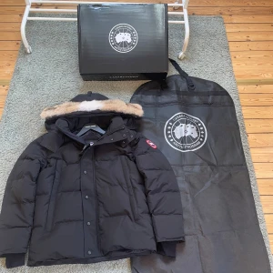 Svart canada goose jacka Wyndham med päls - Säljer en svart dunjacka från Canada Goose i storlek M. Den är helt oanvänd och det finns inga konstigheter med den alls . Allt orginallt medföljer som finns på bilderna dustbag och box.Perfekt för kalla dagar med sin tjocka, quiltade design och snygga look. Ifall du är intresserad och har frågor är det bara att kontakta mig.