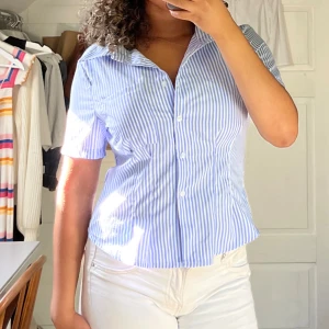Blårandig kortärmad skjorta - Snygg kortärmad skjorta med blå och vita ränder, älskar den! Skjortan var tyvärr tajt för mig vid brösten och därför lite obekväm. Har vanligtvis S/M men lutar mer mot M och BH 85c. 