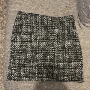 Svartvit rutig kjol från Å - Snygg svartvit rutig kortkjol från Å i grovvävt material med diskret dragkedja i sidan. Kjolen har en klassisk rak form och känns både trendig och stilren. Perfekt att matcha med boots eller en skinnjacka för en cool look.personligen tycker jag det är mer än 38 i storlek 