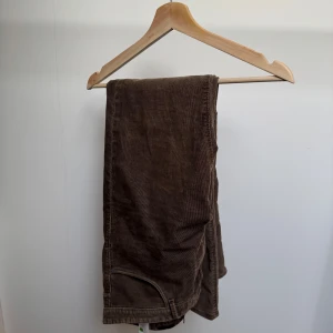 Bruna manchesterbyxor Massimo Dutti - Snygga bruna manchesterbyxor från Massimo Dutti i slim fit-modell. Byxorna har klassisk design med smal passform och är tillverkade i mjuk manchester som ger en stilren och trendig look. Perfekta för dig som gillar en clean och modern stil.