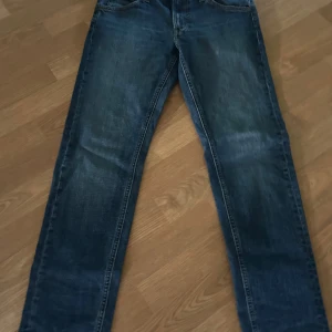 Blå jeans från Lee med raka ben - Snygga blå jeans från Lee med klassisk femficksdesign och raka ben. Jeansen har mellanblå tvätt och tydliga sömmar, samt ett brunt Lee-läderpatch bak i midjan. Perfekta för en avslappnad och stilren look.