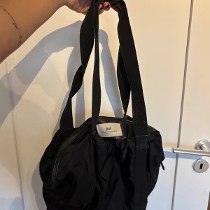 Svart shoppingväska från DAY - Stor svart shoppingväska från DAY Birger et Mikkelsen med långa, breda axelband och dragkedja upptill!