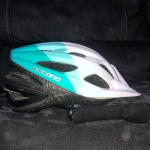 Turkos och vit cykelhjälm Occano - Snygg cykelhjälm från Occano i turkos och vit med sportig design och flera ventilationshål. Justerbar passform och lätt vikt på 250g. Perfekt för dig som vill ha en fräsch look när du cyklar. Märkt med Occano på sidan.