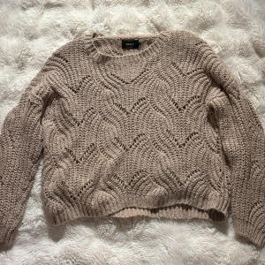 Beige stickad tröja från ONLY - Säljer en beige stickad tröja från ONLY i storlek M. Tröjan har ett snyggt hålmönster och rund hals. Den är långärmad och har ribbade muddar vid ärmslut och nederkant. Perfekt för dig som gillar mysiga och trendiga plagg.